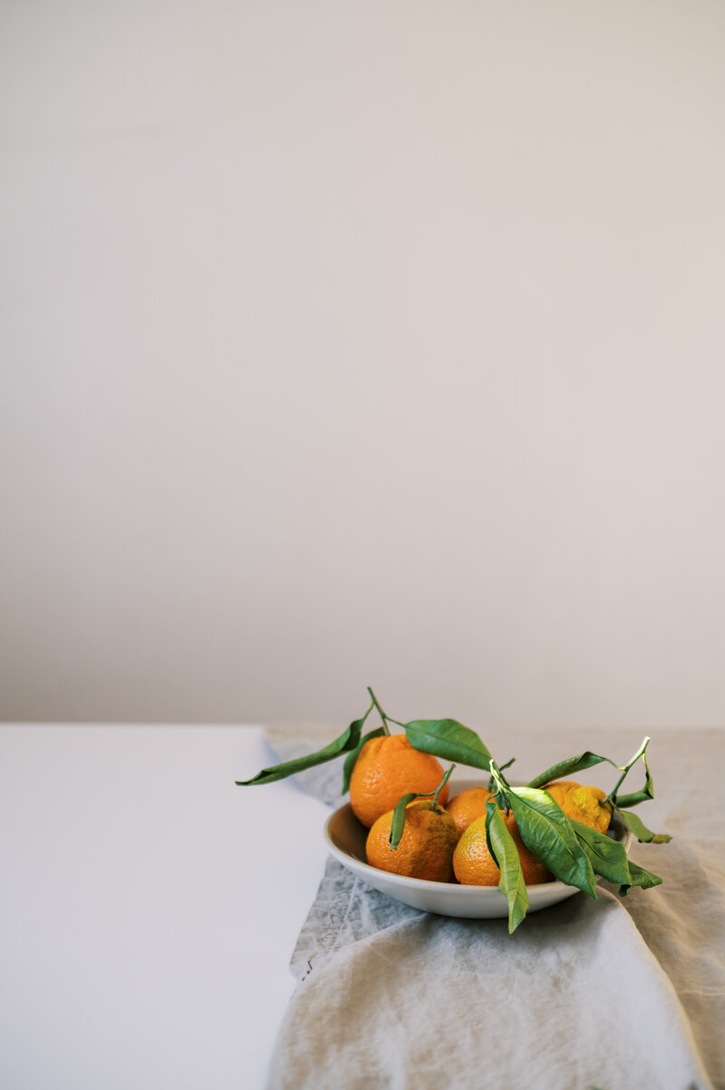 Oranges in a ceramic bowl on linen cloth
