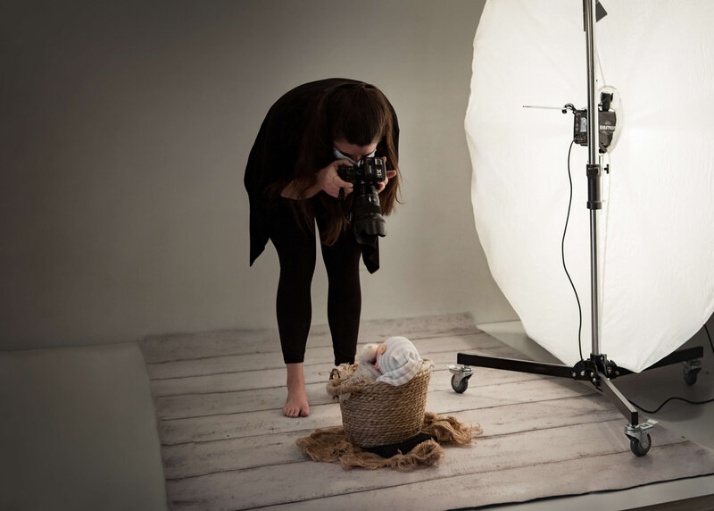 Newborn Photographer taking a photo of a swaddled newborn  baby in a basket
