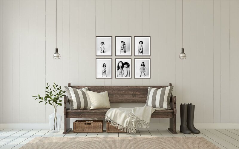 sisters in black and white portraits hanging in frames above a wooden indoor bench