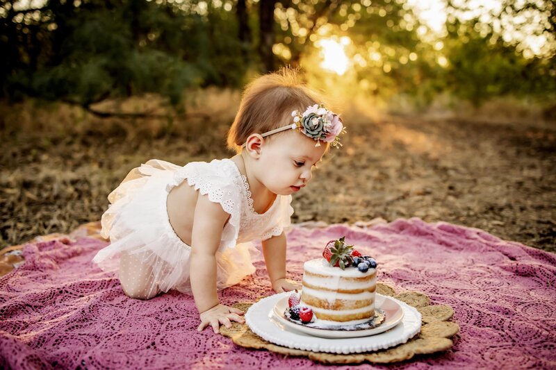 one year old girl eats birthday cake at a cake smash session