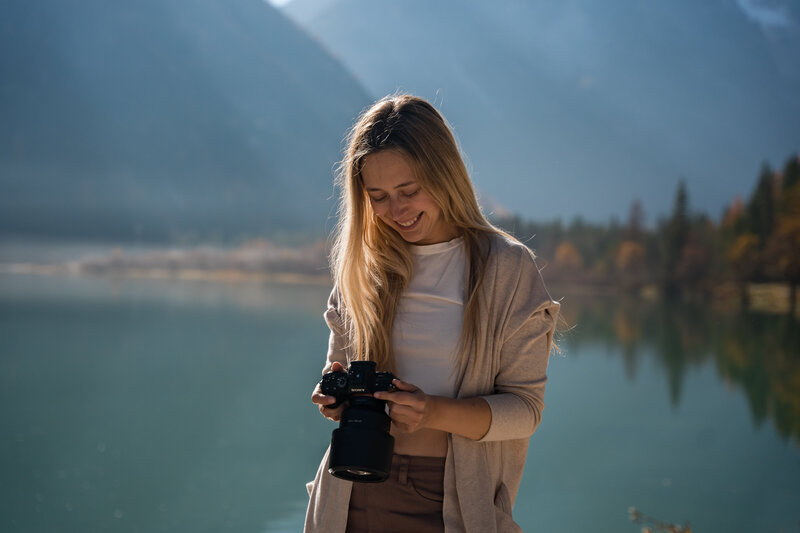 Shawna Rae, Dolomites Elopement Photographer, looking at a photo she just took at a lake