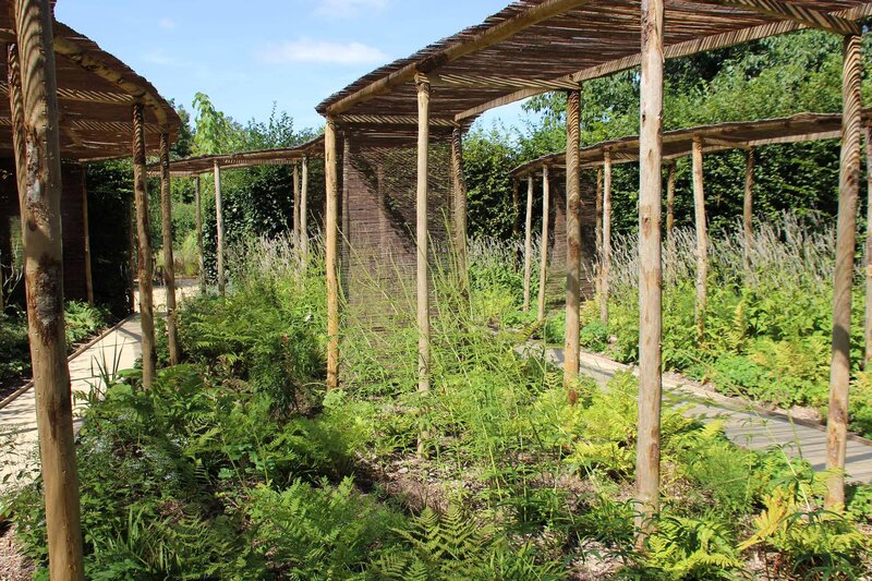 Chemins en bois avec pergolas arrondies sur pilotis, plantations et fleurs