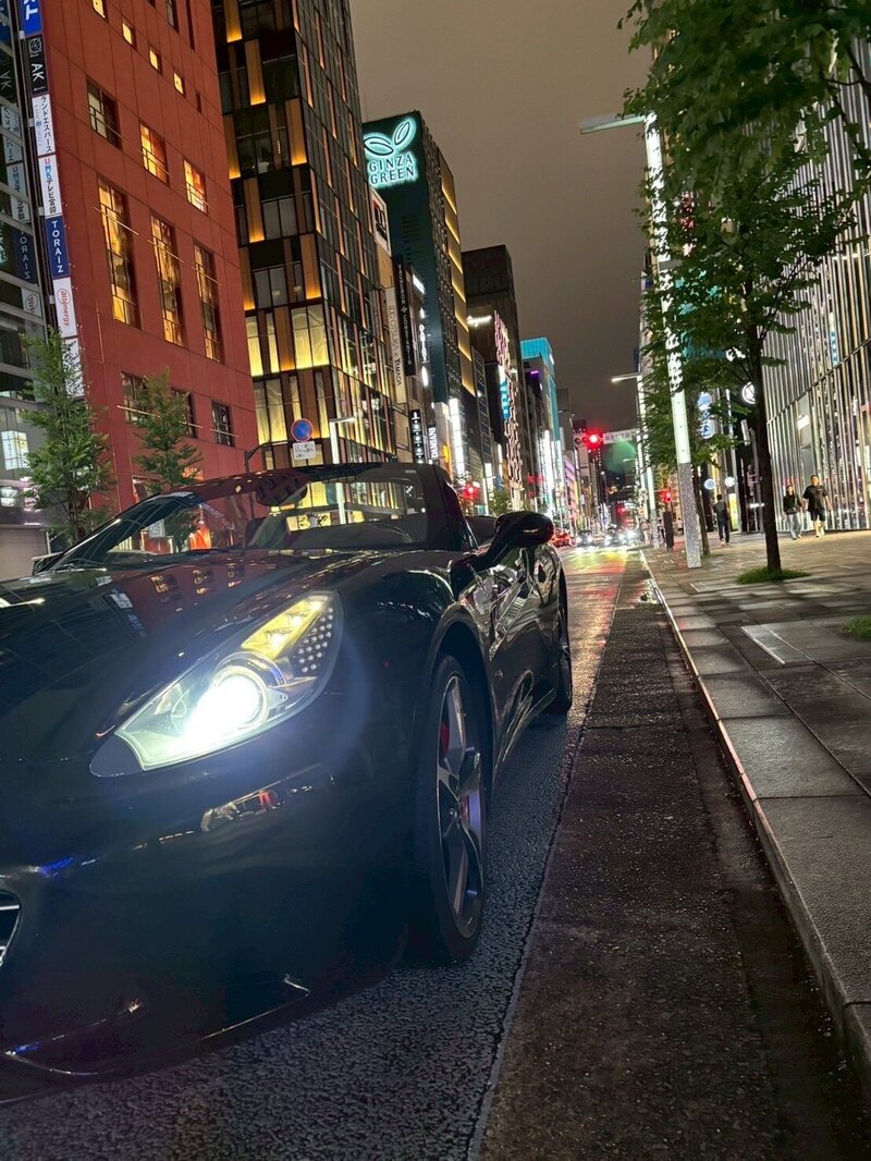 Front view of a black Ferrari California convertible parked along a Tokyo street