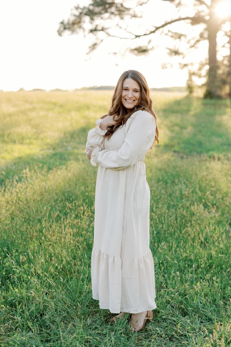 Woman smiling in a field during golden hour captured by Luke and Ashley Photography, Destination Wedding Photographers.