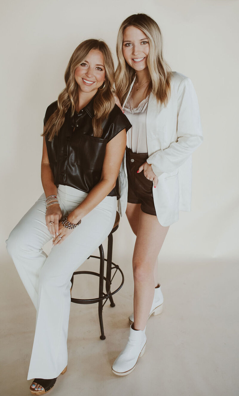 two women smiling at the camera while standing next to each other