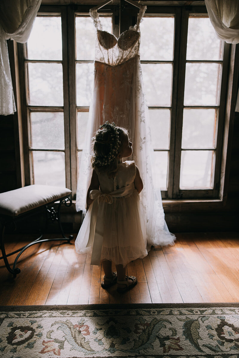 Flower girl looking up at a wedding dress