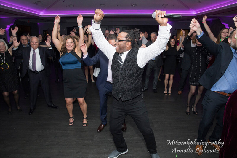 DJ and guests dancing with arms raised during high-energy party in Chicago with Charizma Entertainment