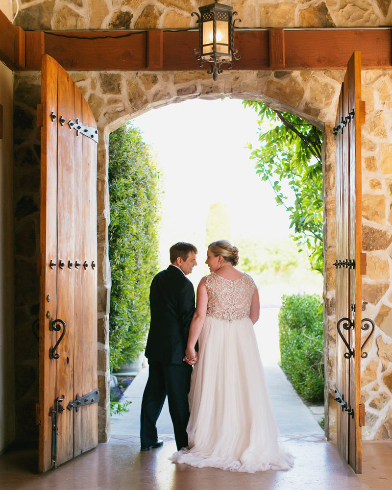 Bride + Groom portrait from behind as they walk out two big doors