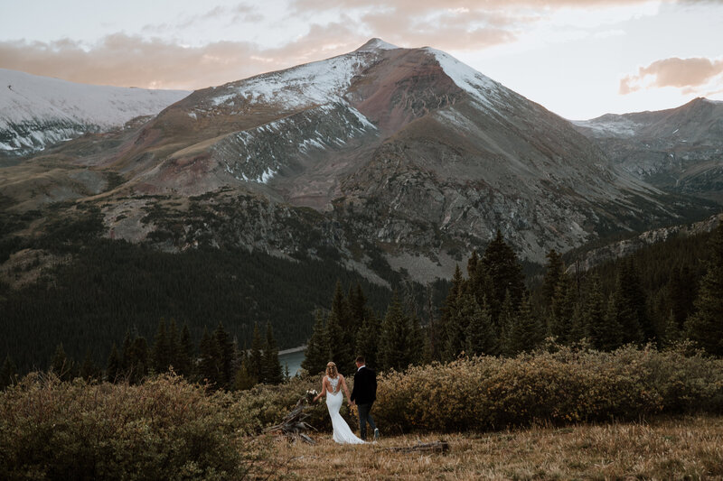Bride and groom walk away through pine forest at golden hour during mountain elopement in Breckenridge.