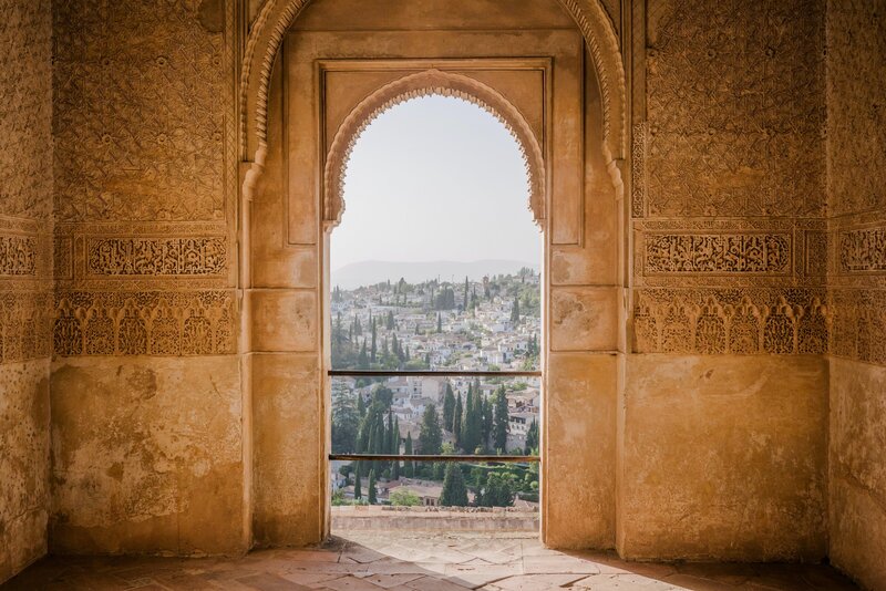 the view of a town from a stone archway