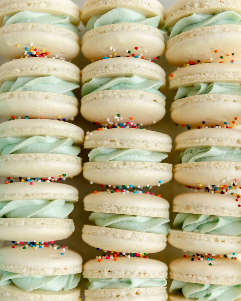 cream macaroons with green filling topped with sprinkles