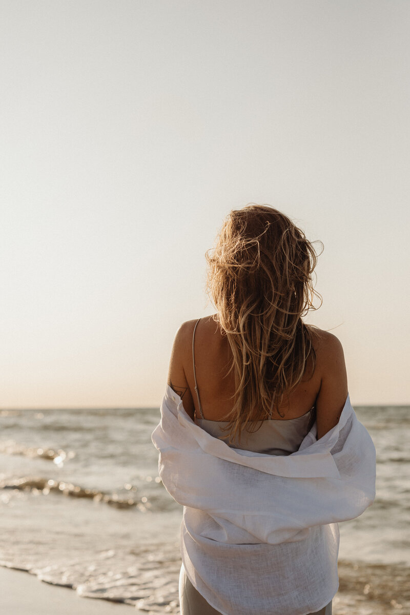 Frau am Strand von Usedom blickt auf das Meer.