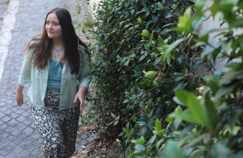 Woman walking up the steps of a cobblestone street next to wall of Ivy