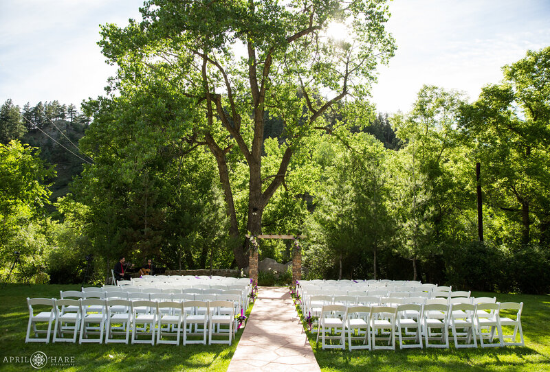 Classy white folding chairs set up for wedding on the lawn at Wedgewood Weddings Boulder Creek Location in Colorado During Summer
