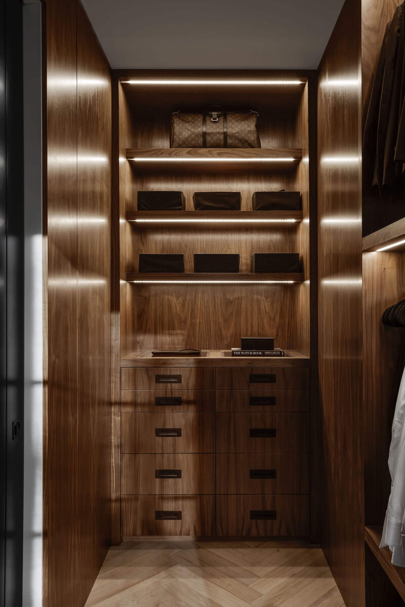  A walnut walk in closet with black accents and LED lighting. 