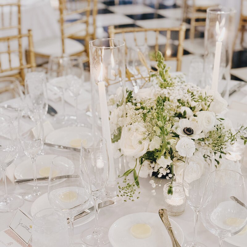 Classic white and gold wedding reception details with white rose floral centerpieces and tapered candles on each table in the ballroom of La Valencia Hotel.