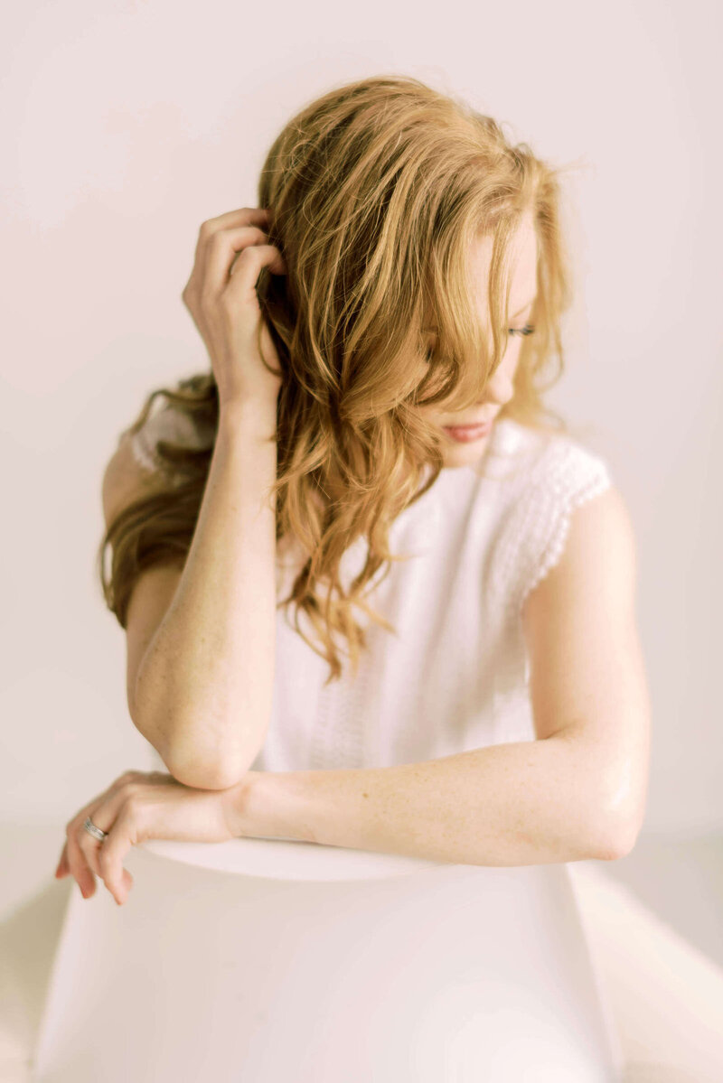 Elegant storytelling wedding photographer sitting on chair with long red hair