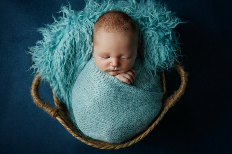 Newborn baby wrapped in blue in studio newborn session