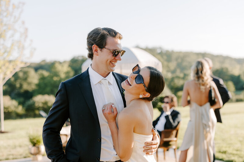 Brunette bride and groom looking happy wearing sunglasses after their Westwind Hills wedding in Missouri, photographed by wedding photographer Jacoby Andrick