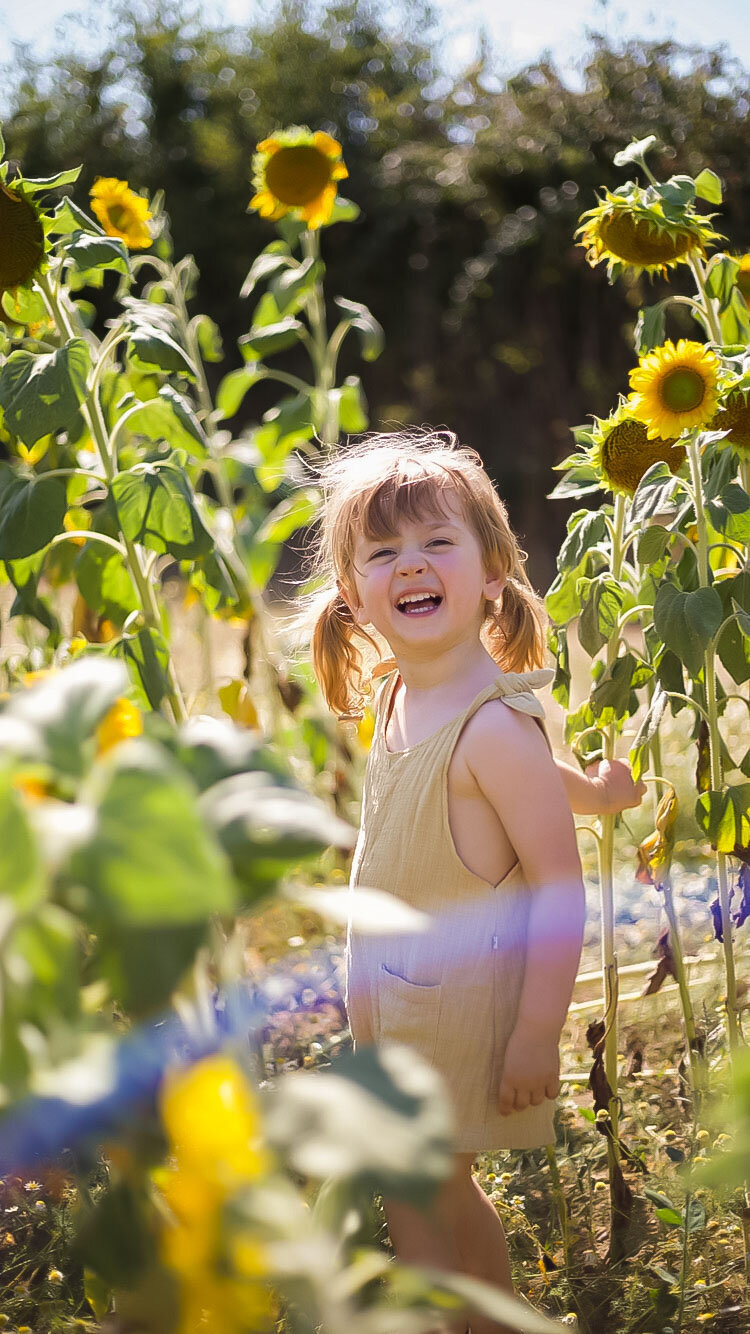 Girl smiles as she is surrounded by sunflowers