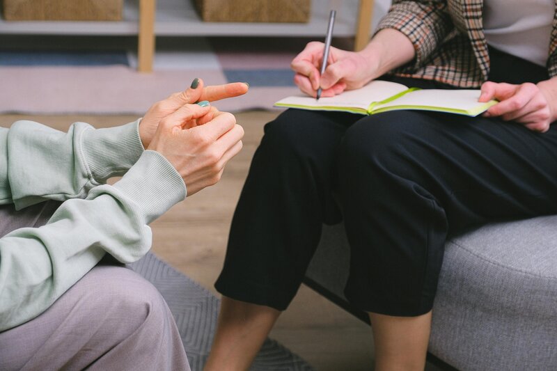 Close-up of a therapist writing in a notebook while speaking with a client—offering compassionate and evidence-based mental health support.