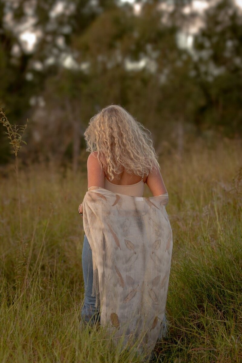 Woman walking in field embracing her beauty and her own Goddess Within.