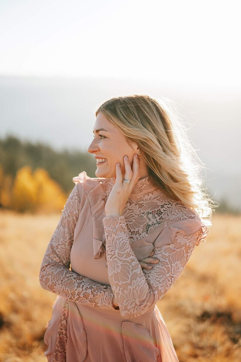 Michelle with a sunny fall Colorado mountain background smiling off to the side.