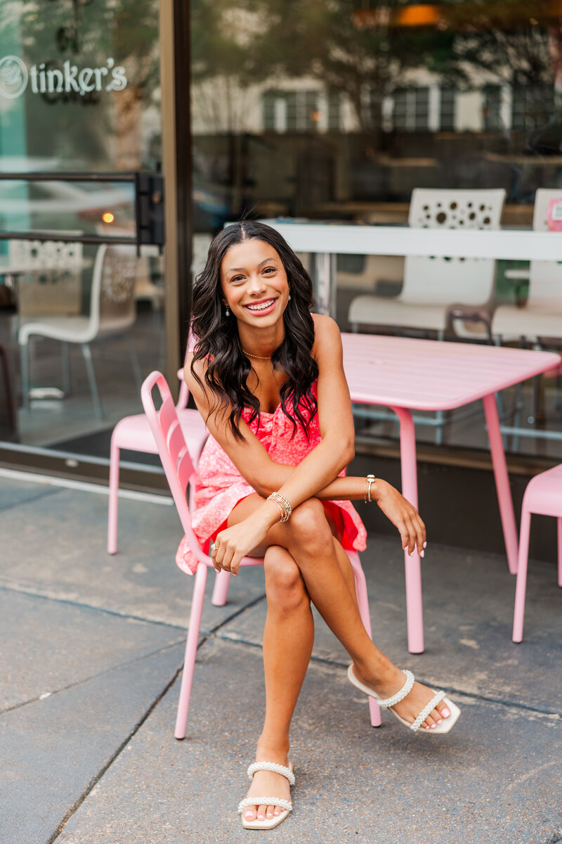 a girl smiling while sitting at a table outside a store