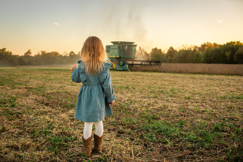 farmgirl watching john deere combine soybeans in field