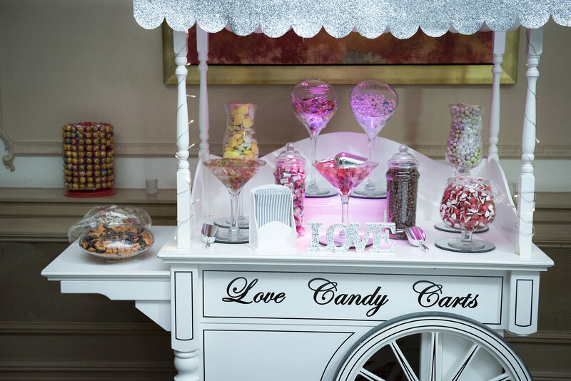 A candy cart at an evening party stocked with jars of sweets.