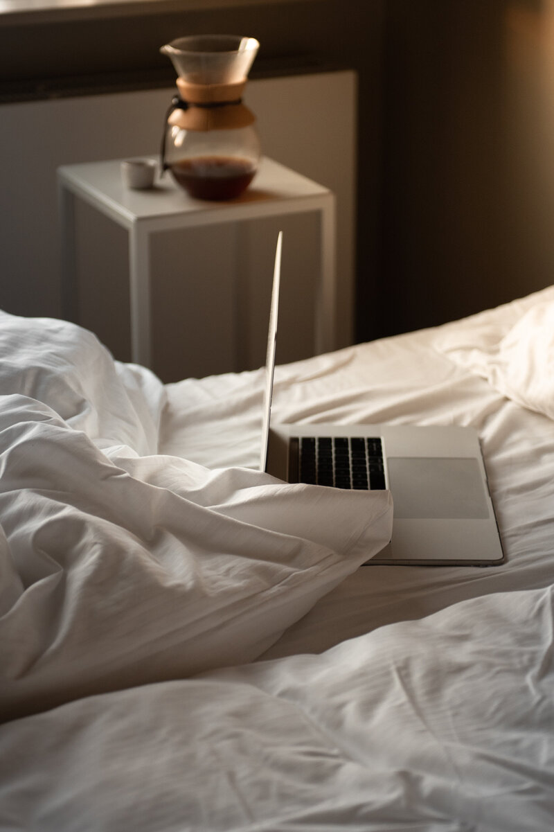 A laptop sits on a bed with white sheets promoting a Las Vegas Boudoir Blog.