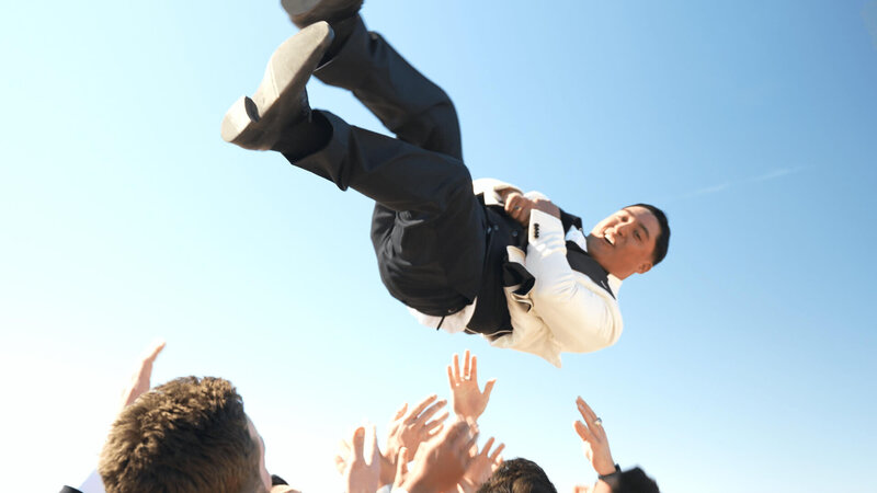 Groom getting tossed in the air by groomsmen
