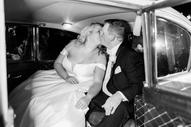 Black and white photo of bride and groom in wedding getaway car