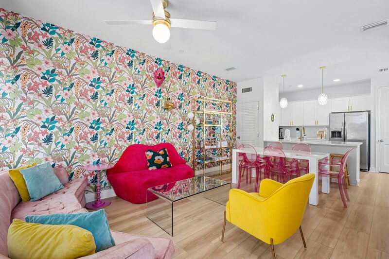 Vibrant, open-concept living and dining area with tropical wallpaper and colorful seating—perfect for family vacations and social media snaps in Panama City Beach.