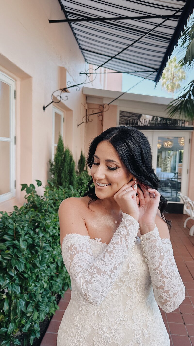 Bride putting on her pearl earrings outside the bridal suite at La Valencia Hotel in La Jolla, California.