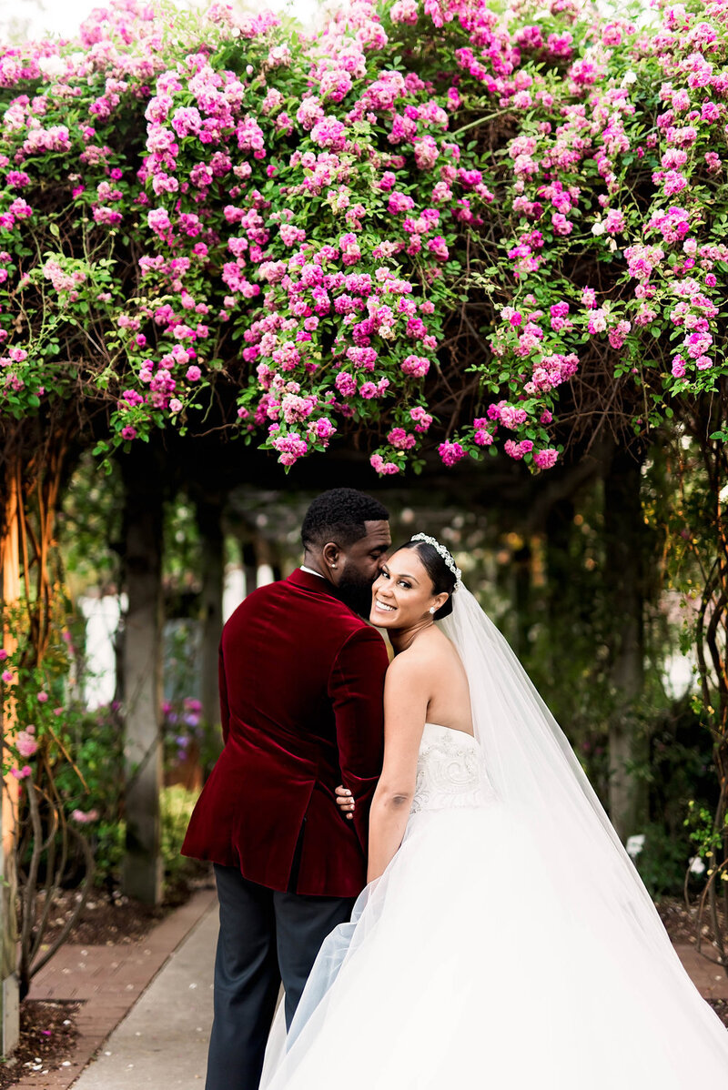 Swank Soiree Dallas Wedding Planner Kerri and Bravion at the Dallas Arboretum and Botanical Garden - Groom kissing Bride in front of pink flowers