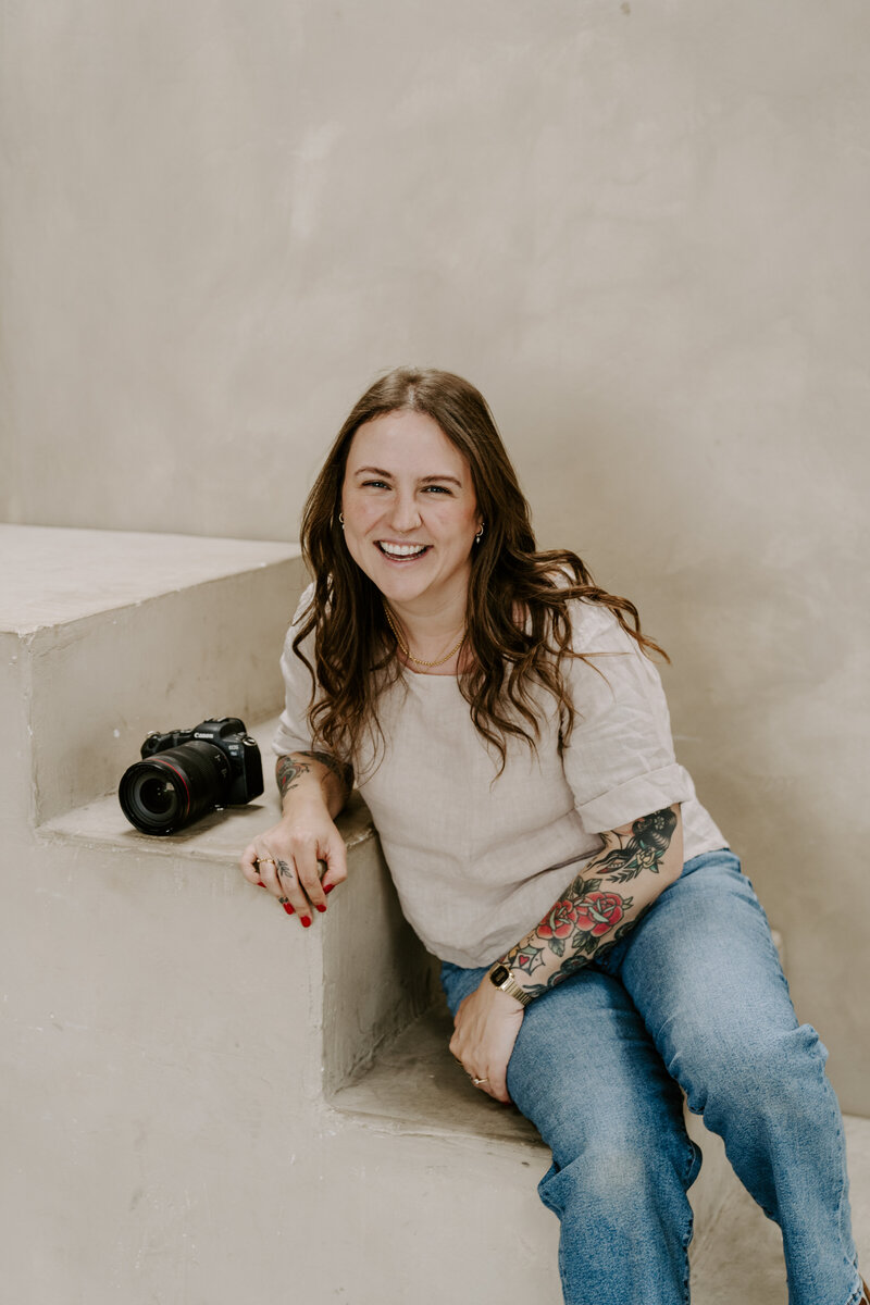 A person sitting on the ground with one knee up looking off to the side 