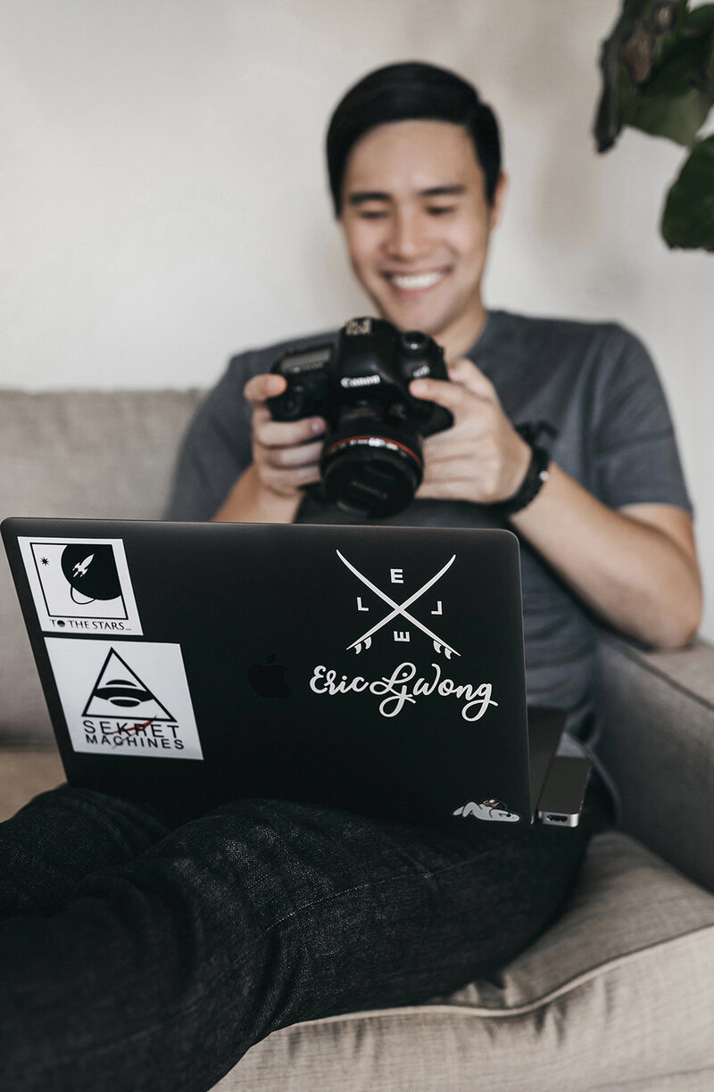 Photographer looking at camera while sitting on the couch with laptop