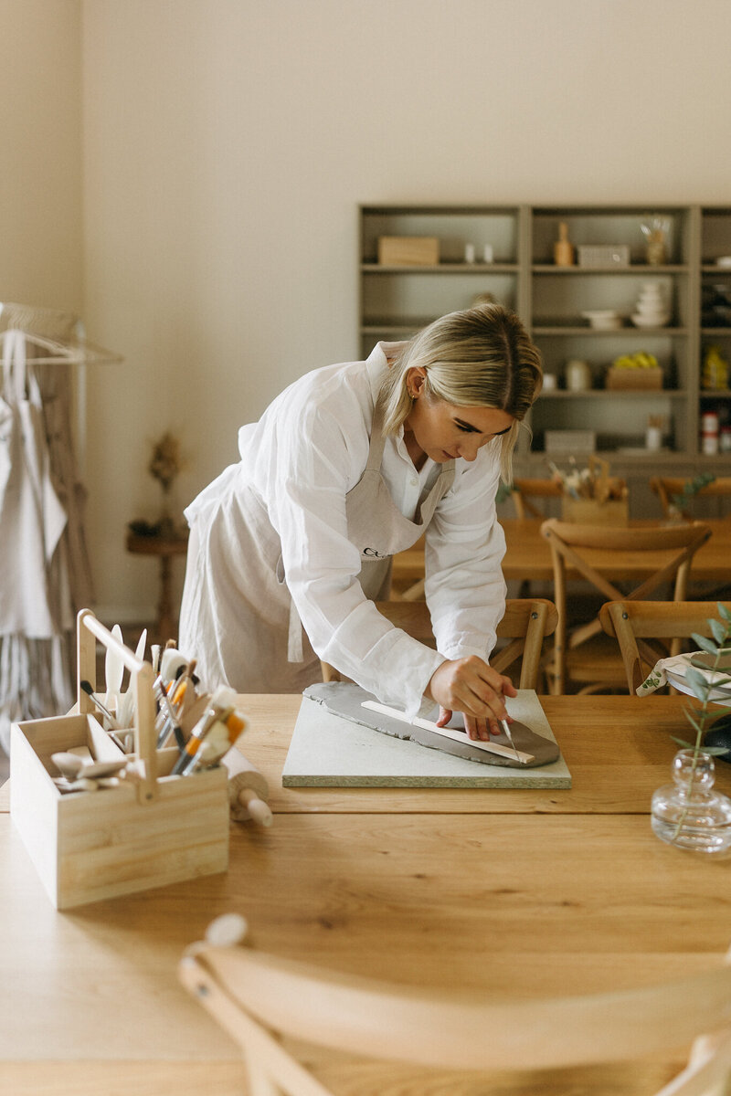 Kuvassa on kolme pientä lautasta päällekkäin joiden päällä on yksi vaalea kulho jossa on pieniä mustia pilkkuja. 