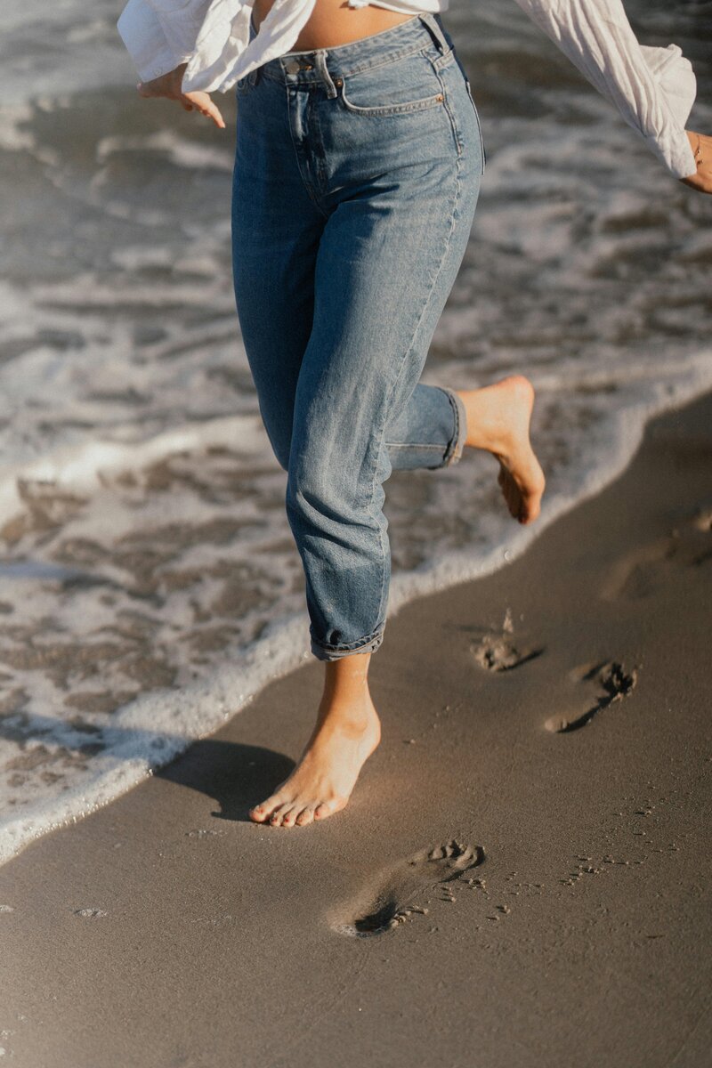 girl running through sand leaving footprints