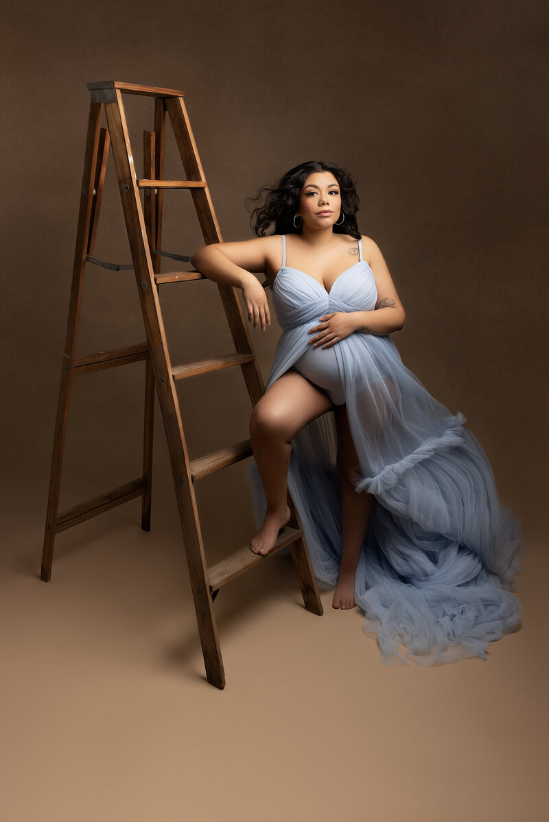 Maternity Photographer, Pregnant Mother in blue dress leans on ladder