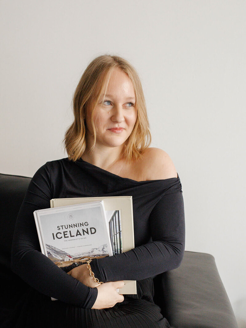 A woman holding travel books posing for a photo