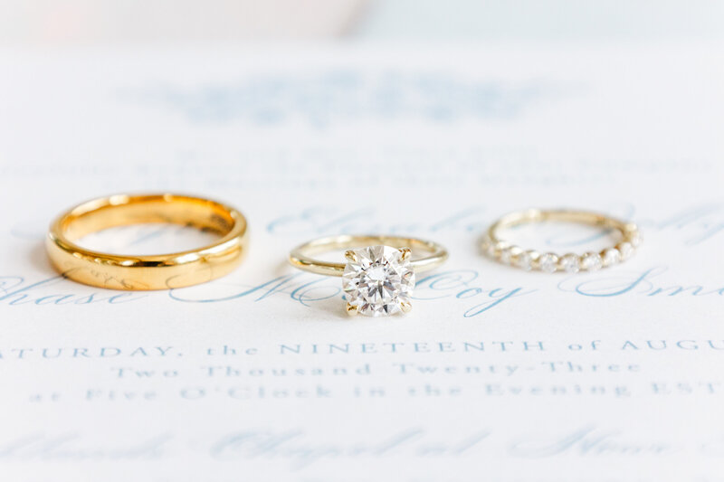 flat lay of wedding rings on top of invitation