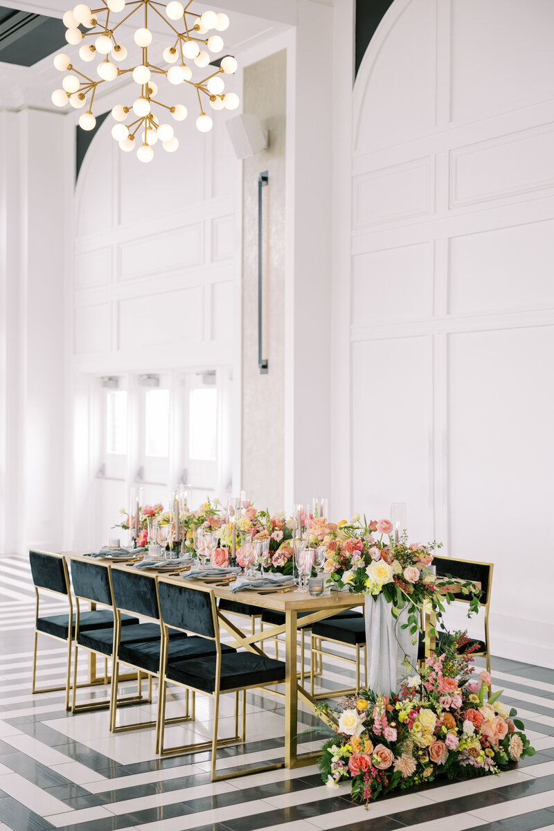 Table with black chairs and floralscape with candles.