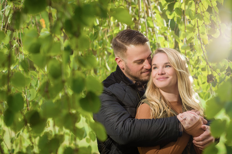 A couple enjoys a serene moment together, surrounded by vibrant greenery, during an outdoor lifestyle session near Phoenixville at Morris Arboretum.