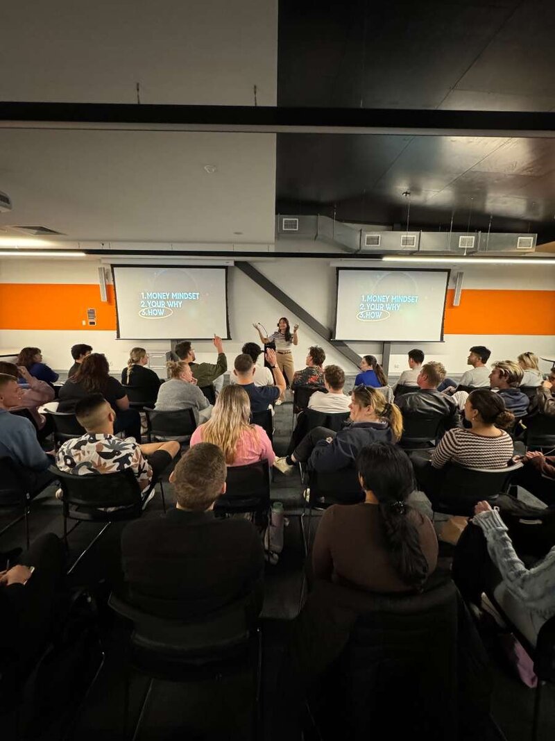 Trang delivering a corporate workshop to an engaged audience in a lecture room.