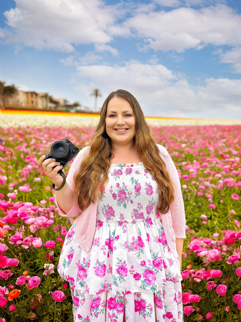Maternity, Newborn, and Family photographer, a photographer stands in a field of flowers holding her camera.