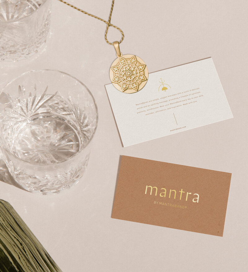 Mantra by Mantra Band business cards, textured glass, and gold medallion necklace