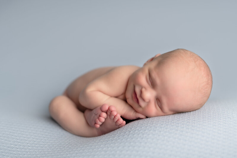 A soft grin in slumber—this baby boy’s expression brings a gentle joy that only newborn magic can deliver.