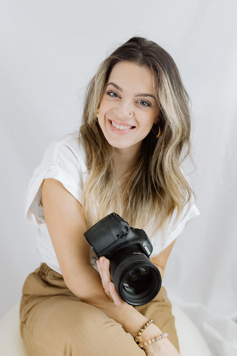 Charity White is a portrait photographer in Aurora and Naperville Illinois, here she smiles and holds her camera.